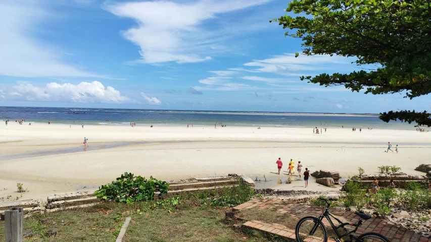 a po from across the beach looking down on people walking and riding