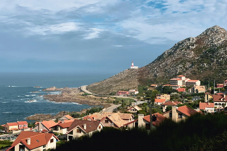 a hill side overlooking the water with houses in the foreground and an ocean on the far side