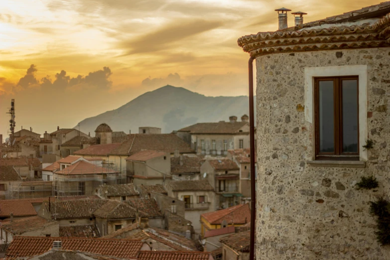 a city with red tiled roofs and buildings on it's sides at sunset