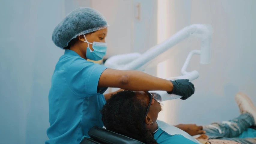 a man getting his teeth brushed by a woman who is wearing surgical gloves