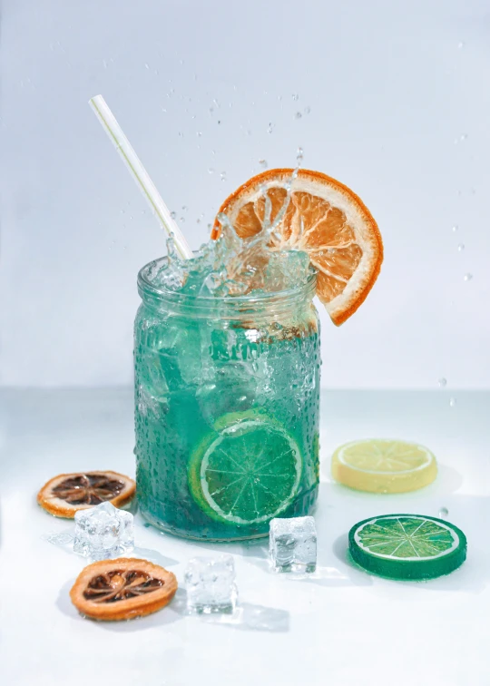 a glass with drink, an orange slice, and ice on a table