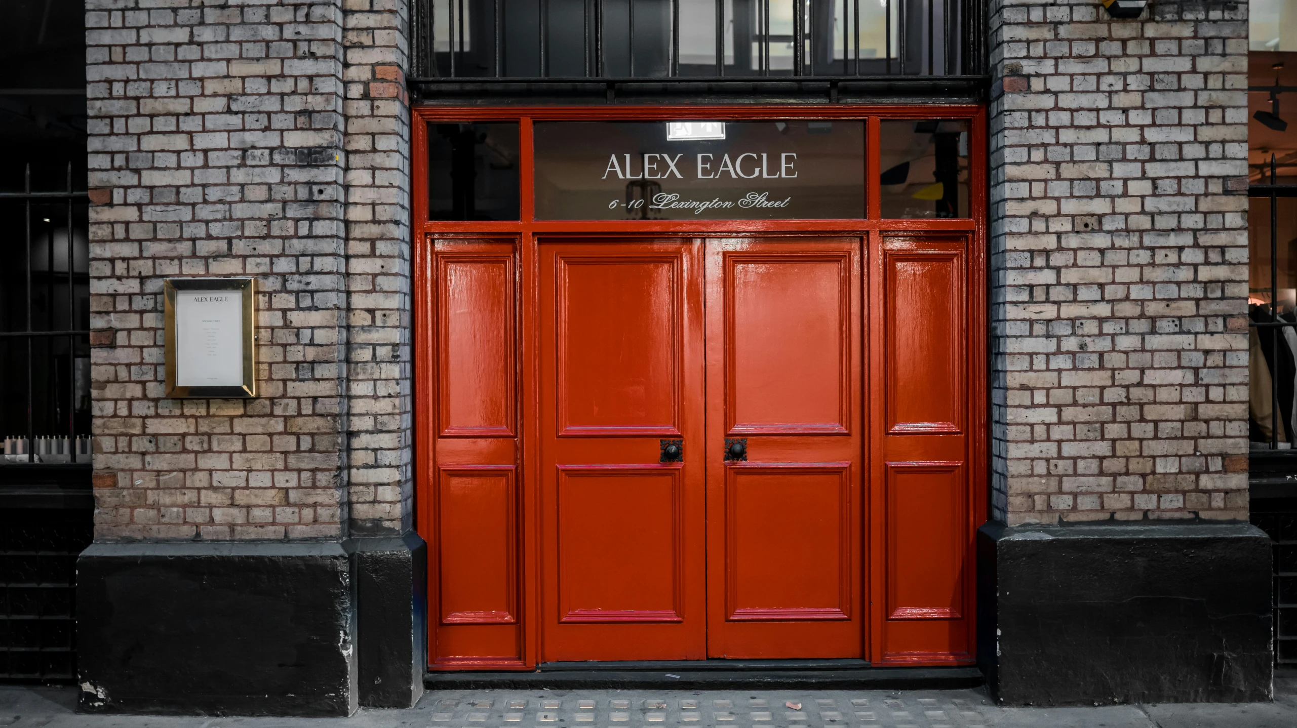 red door that is located in front of a tall brick building