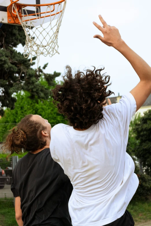 two guys playing basketball on an outside court