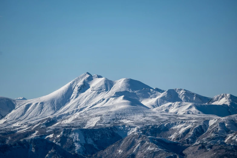 a snow capped mountain range with one plane flying over it