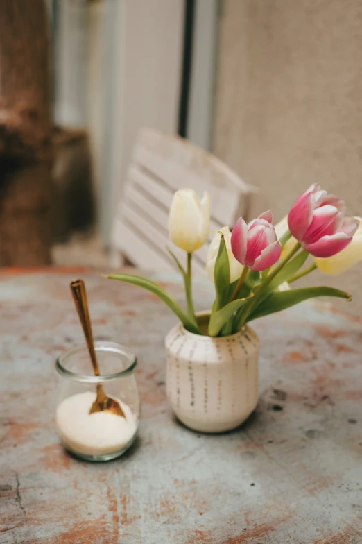 a white vase filled with pink and yellow tulips on top of a table