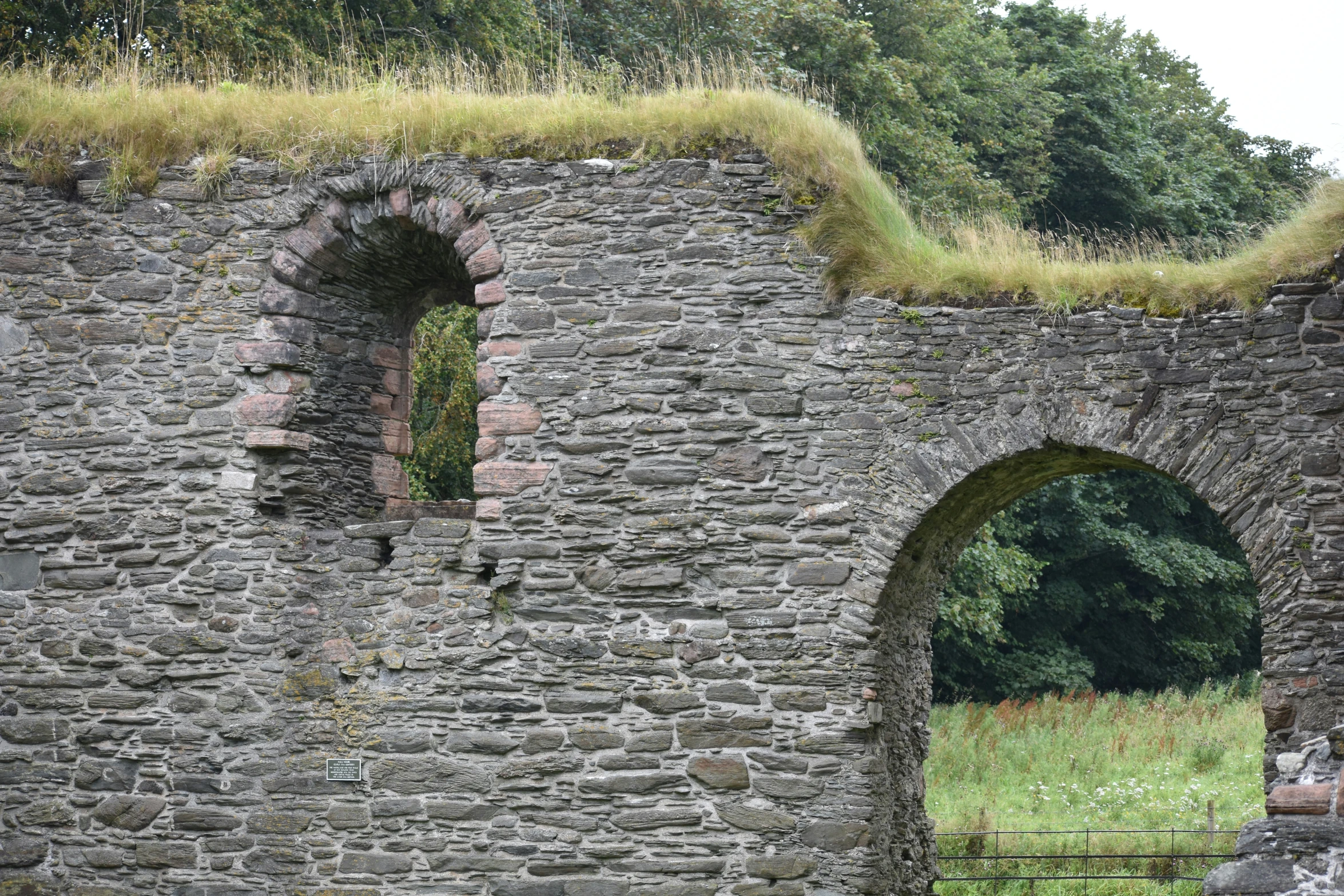 an archway leading to the back of an ancient stone building with grass growing on top