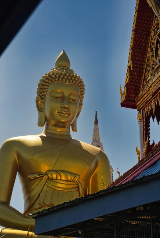 a large gold buddha statue in front of a golden pagoda