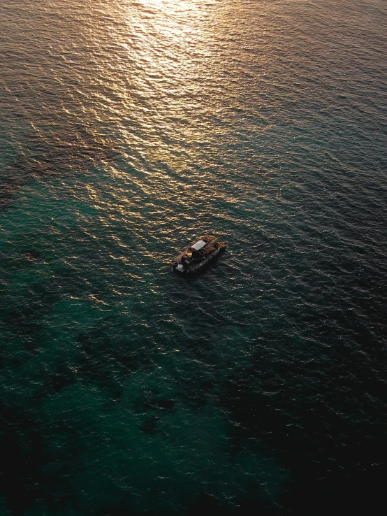 a boat sailing on the ocean at sunset