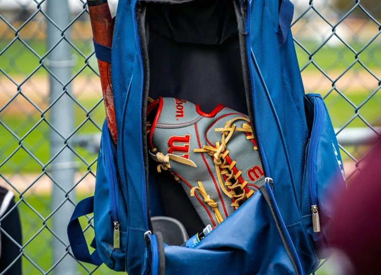 a blue backpack with a baseball glove sitting inside of it