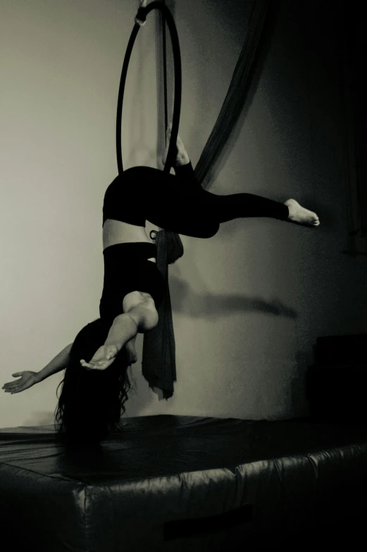 woman suspended by hoop in the air and holding onto wall