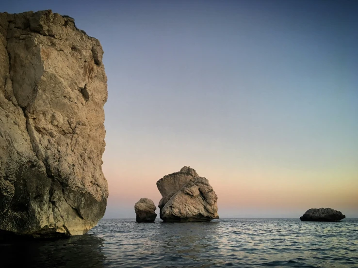 two very large rocks in the water next to the beach