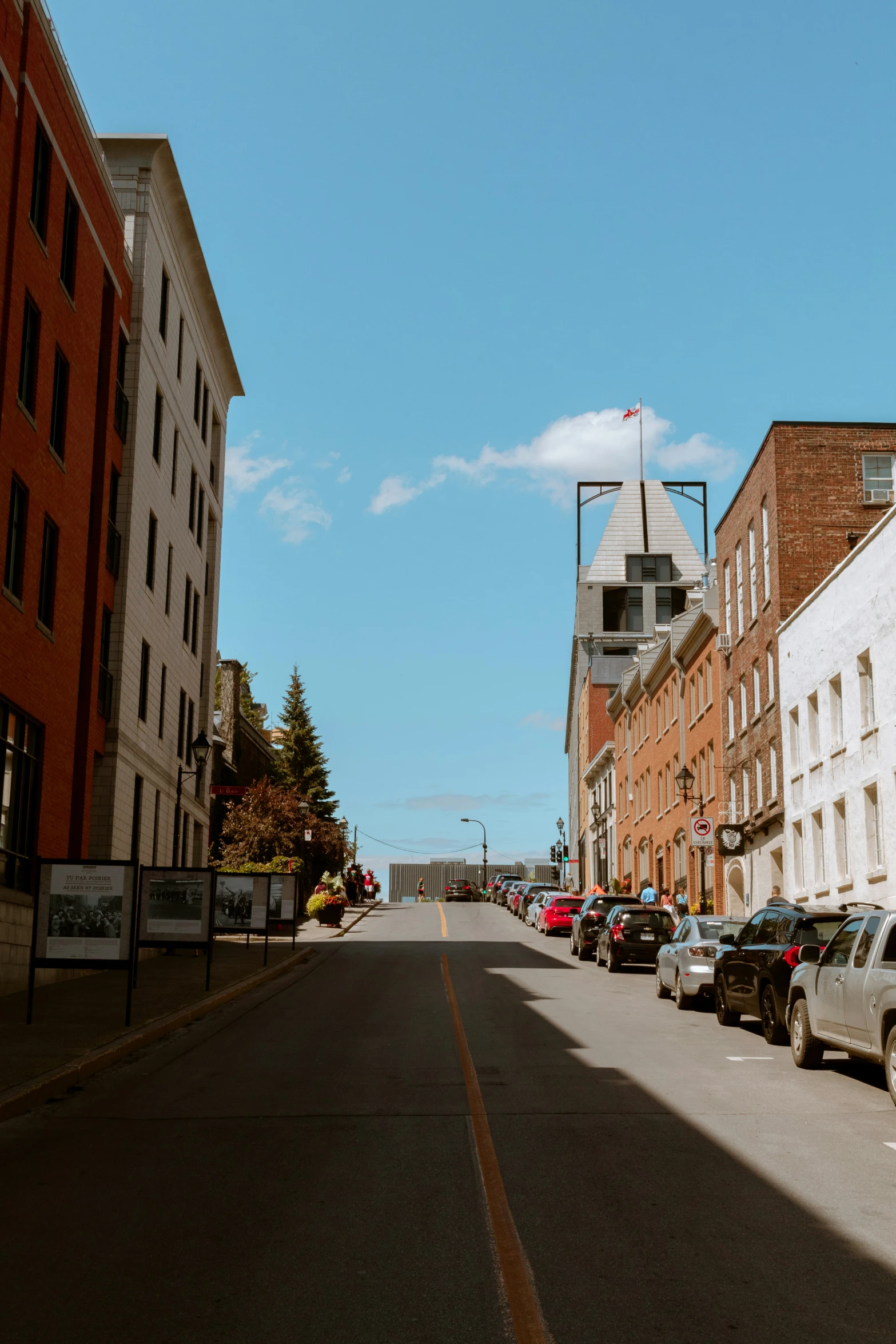 the cars are parked along the street lined with brick buildings