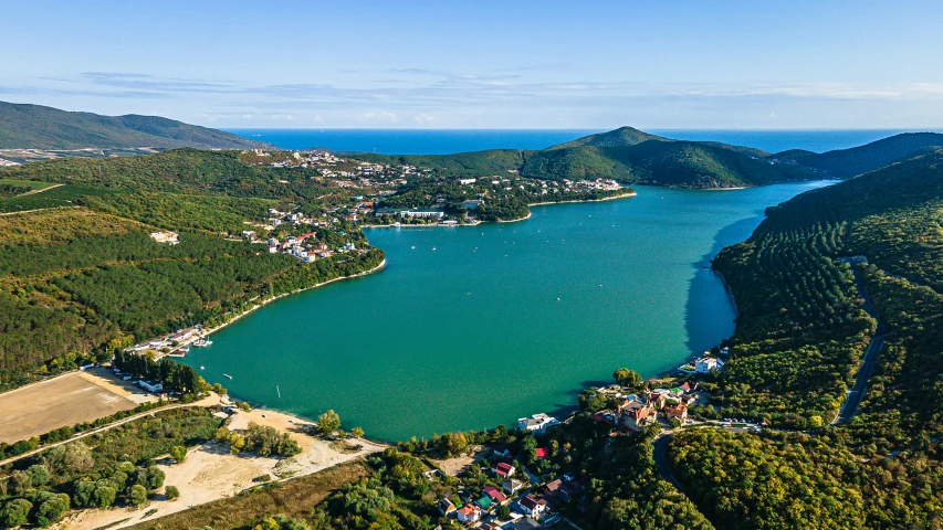 a lake surrounded by a green hillside and a large body of water