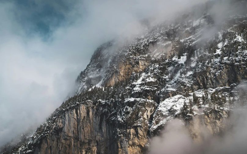 the top of a mountain is shrouded in clouds