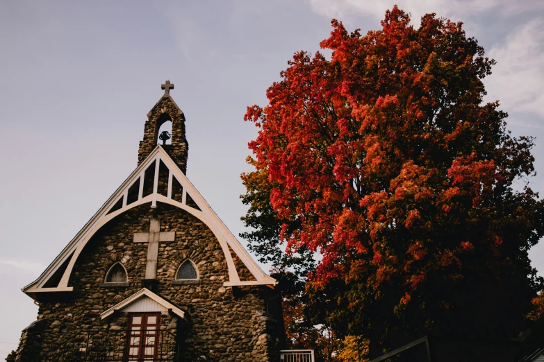 a church building with an attractive steeple, surrounded by trees with red leaves