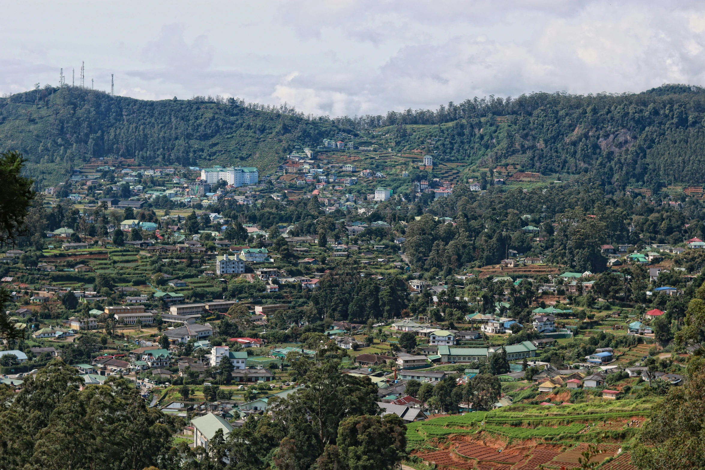 city surrounded by forested mountains and green hills