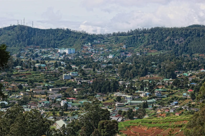city surrounded by forested mountains and green hills