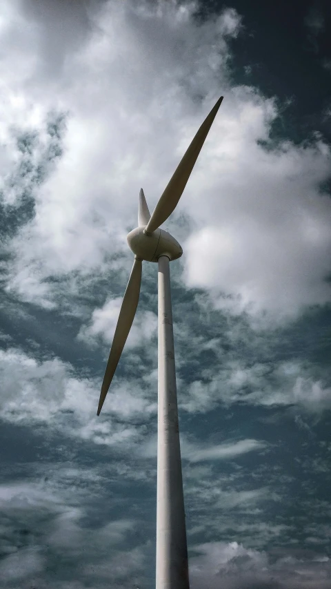a wind turbine with large wings and the sky in the background