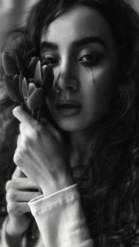 black and white image of woman holding flower in hand