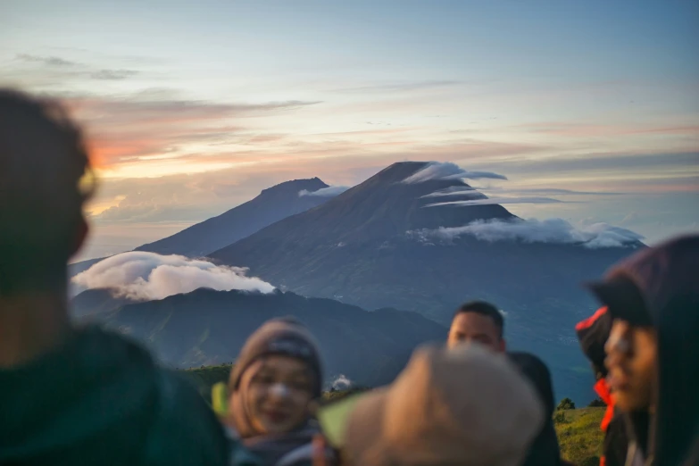 people standing on a hill watch the sun go down