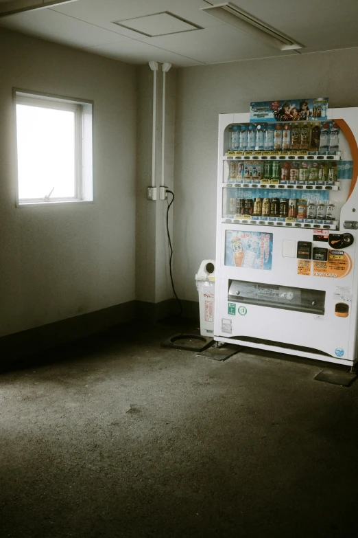 a soda machine sits in a dark room with a window