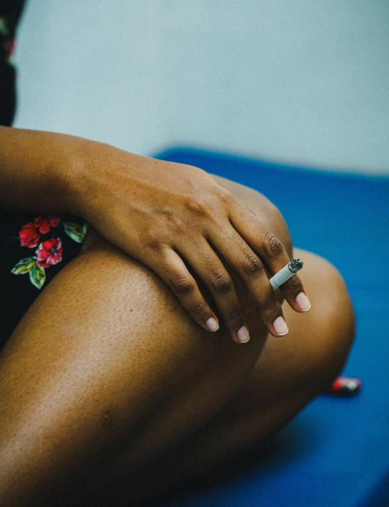 a woman with pink fingernails sitting on a bed