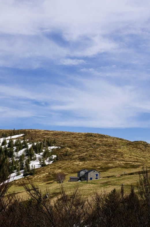 the mountain side is covered with snow and a few trees on either side of the house