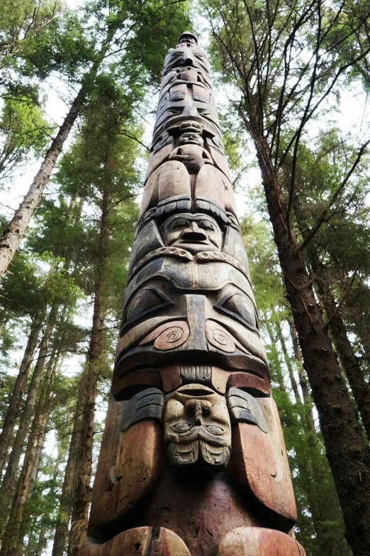 a wooden carving depicting different faces is in the woods