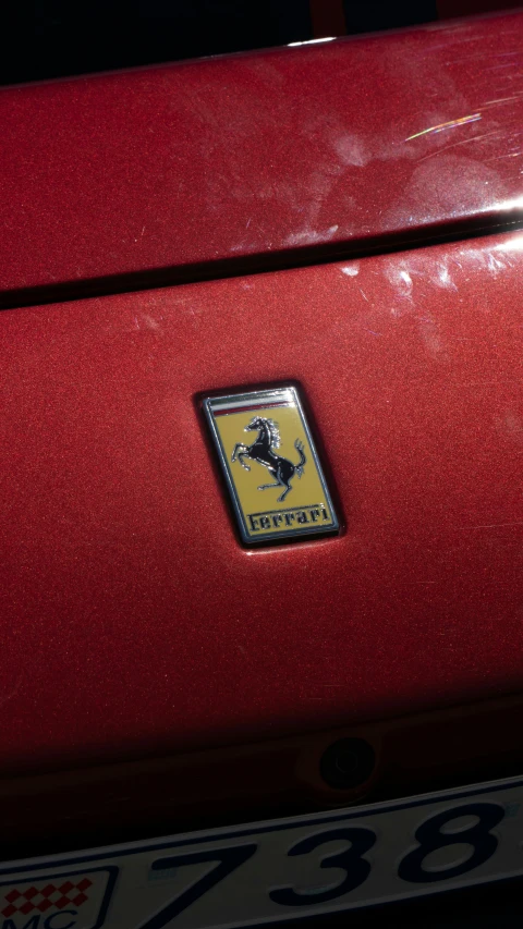 a close up of the tail end of a red car with a yellow ferrari emblem