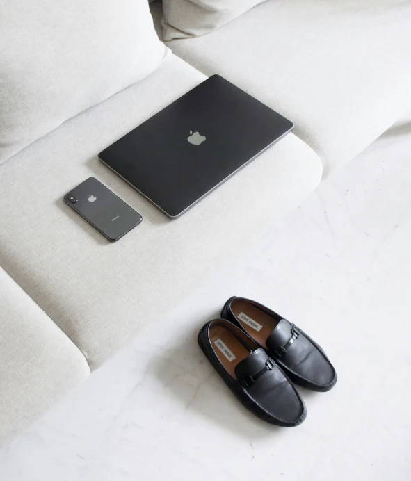 black loafers a laptop sitting on top of a white couch