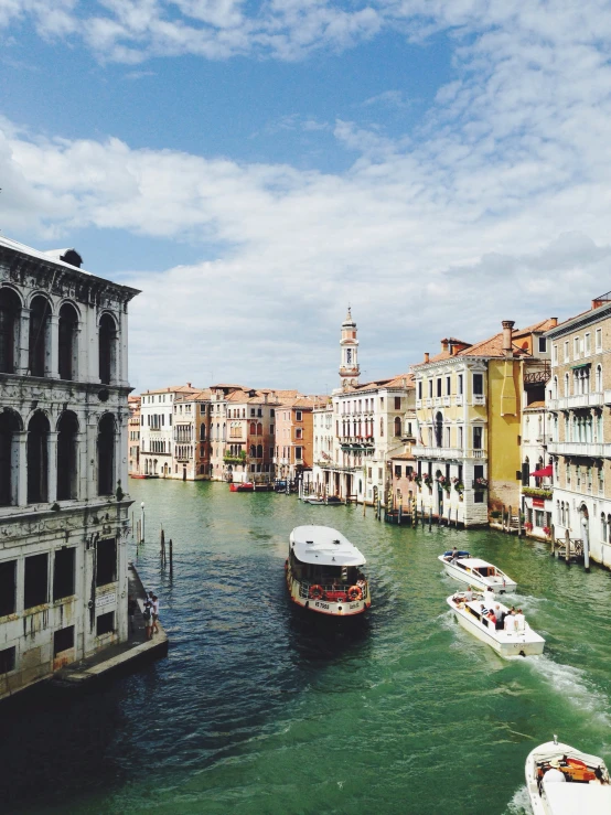 boats go down a canal in venice with buildings on the other side