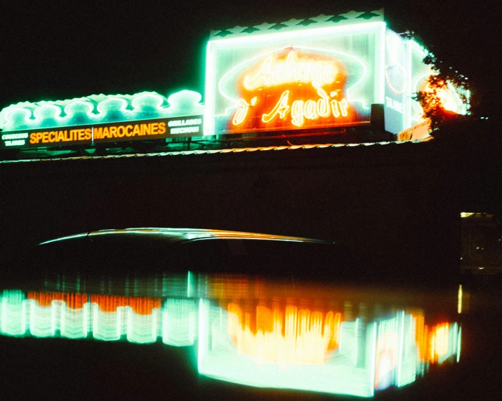 illuminated signs above a bridge on a dark river