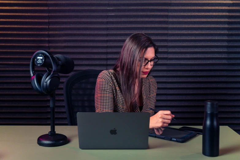 a woman sitting in front of a laptop computer on top of a desk