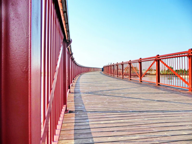 red steel supports a bridge that's being used to cross the river