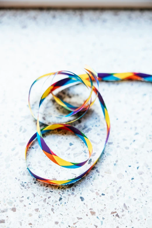 a rainbow colored multicolored ribbon laying on top of a white surface