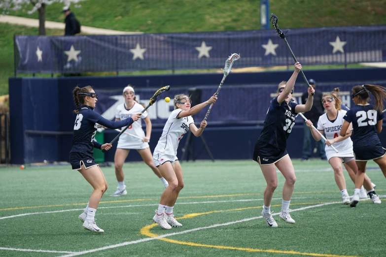 girls holding lacrosse sticks standing next to each other on a field