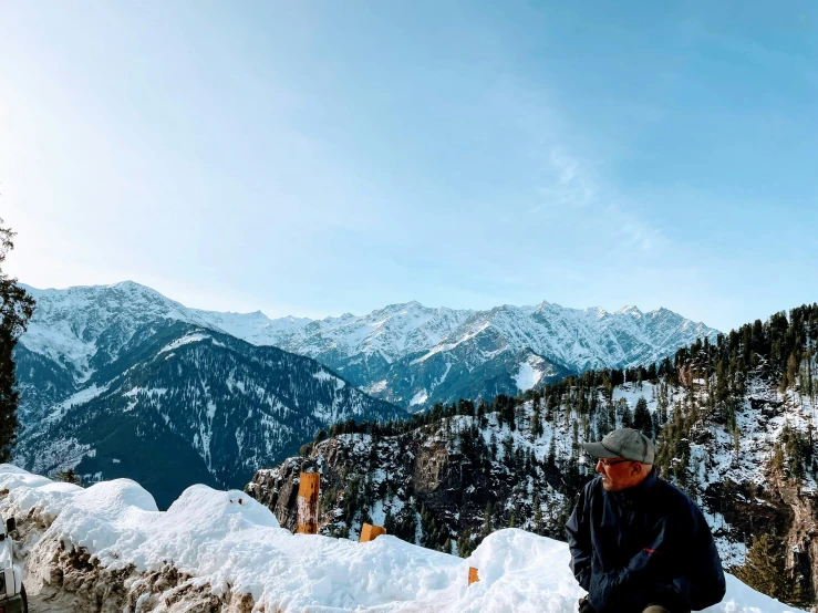 man kneeling at the bottom of a snowy hill, on a sunny day