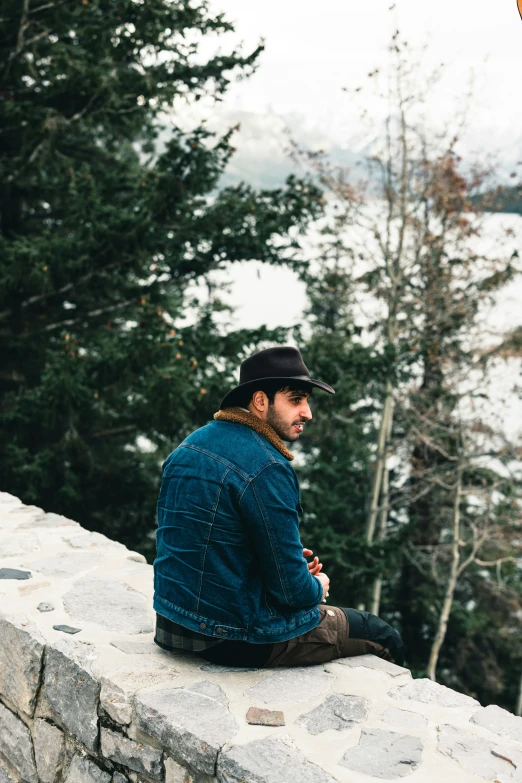 the man in a hat is sitting down by a wall