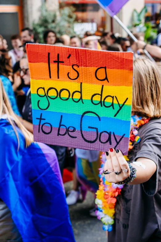 a woman is holding up a sign that says it's a good day to be gay