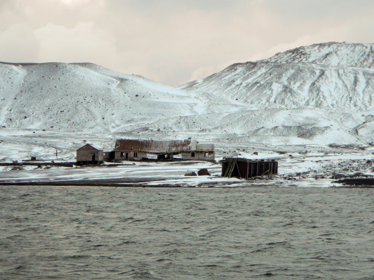old fishing shack in winter with mountains and snow