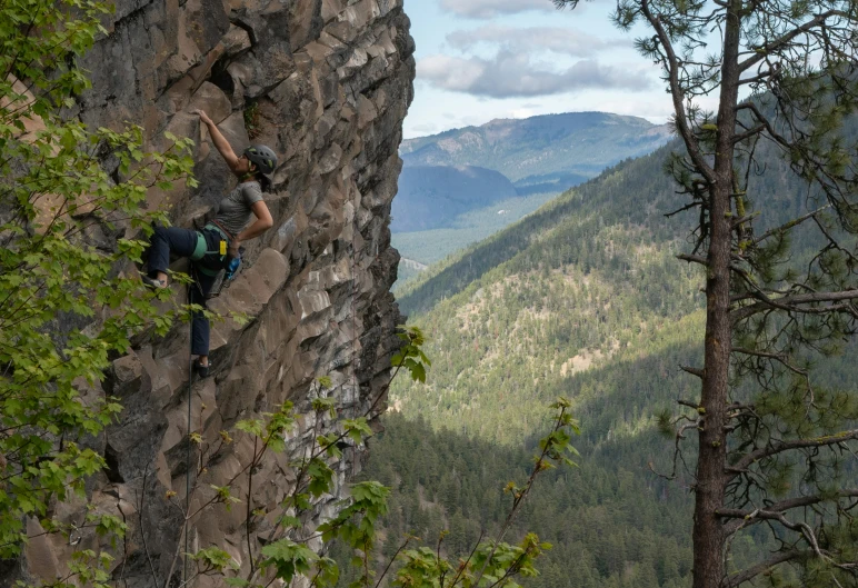 man with backpack climbing on cliff face of mountain