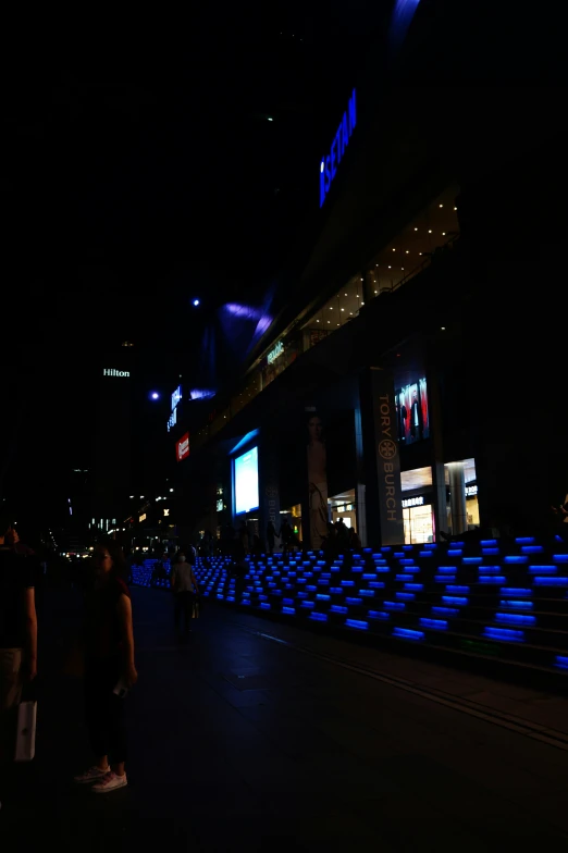 people standing in the dark with an illuminated stadium