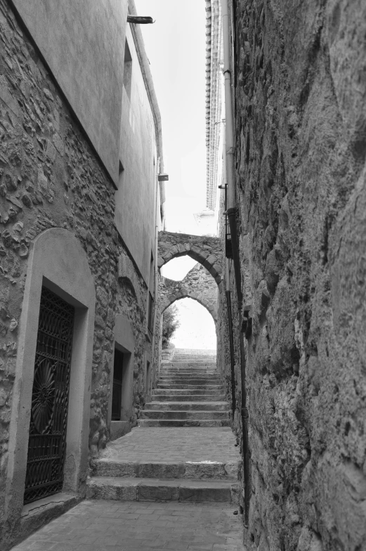 a narrow alleyway lined with stone walls and arches