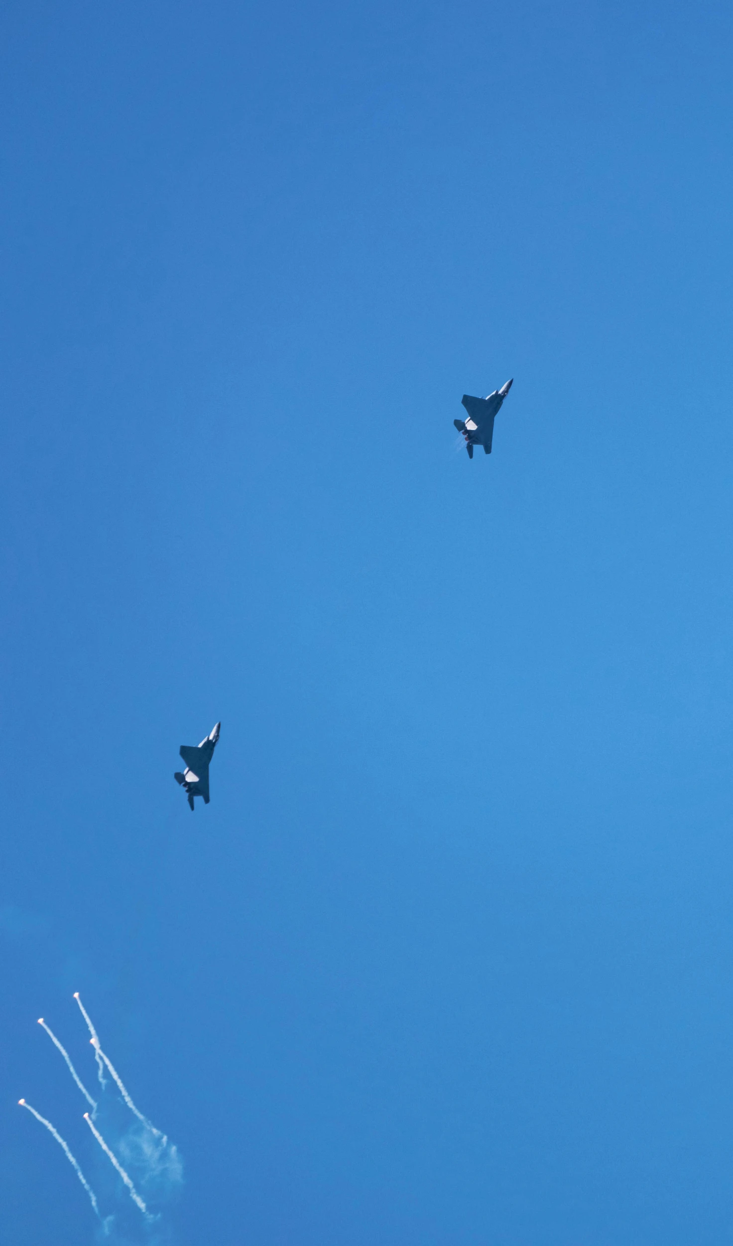 two fighter jets fly in a blue sky