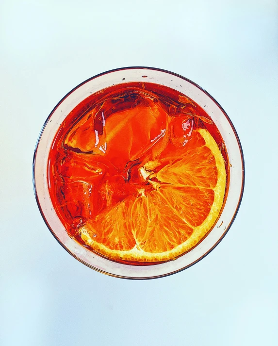 a glass of juice with oranges sitting on the side