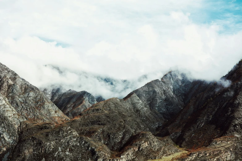 a group of mountains sitting under clouds on top of them