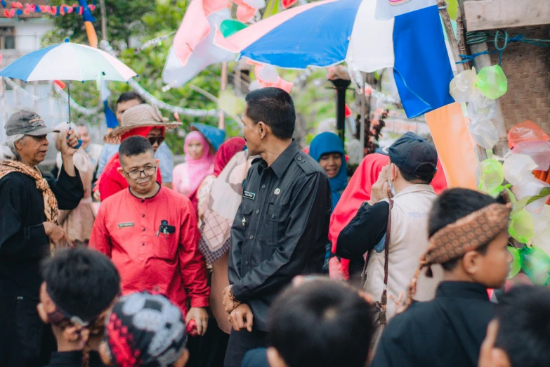 several people stand and talk under blue umbrellas