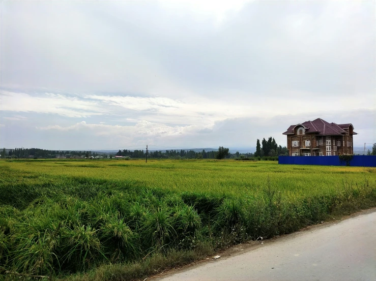 a house sits in the middle of a large grassy field