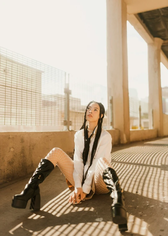 a woman sitting on the ground wearing knee high boots