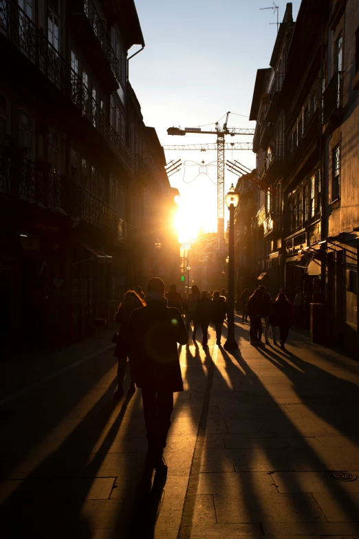 a group of people walking down a street past tall buildings